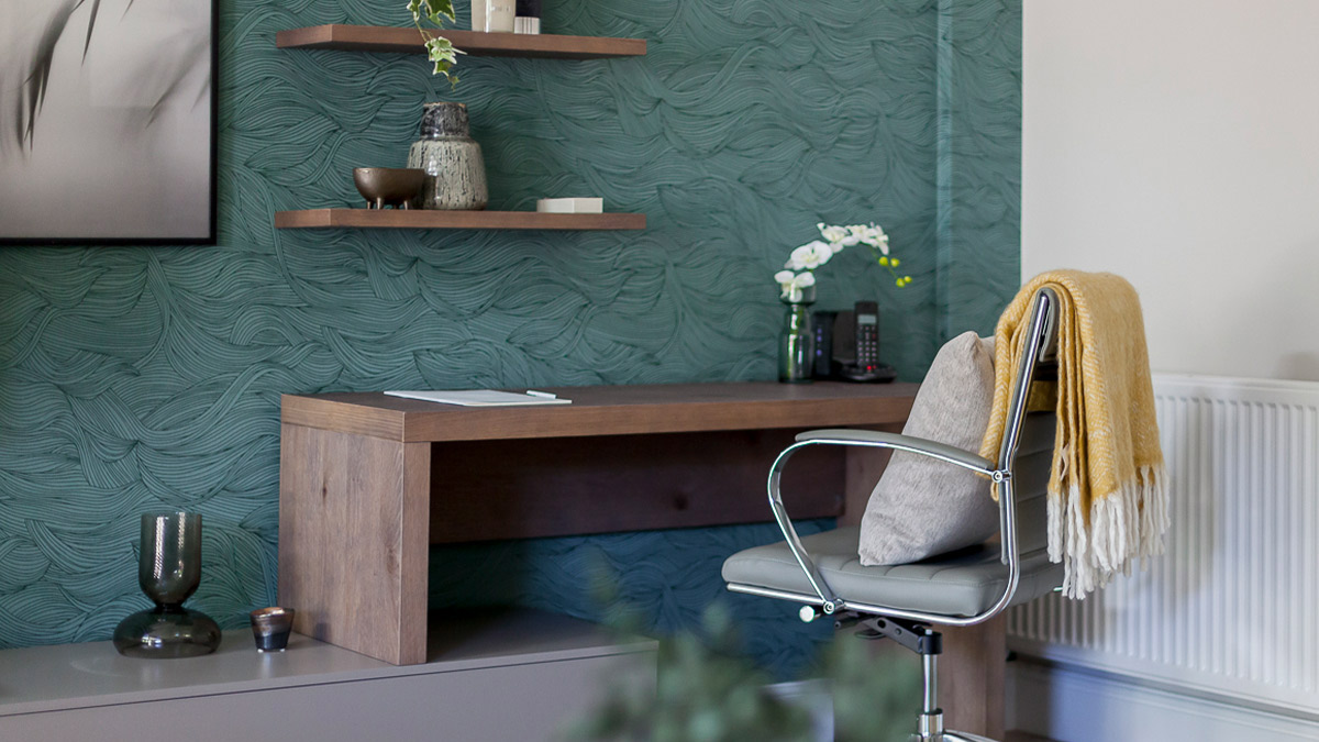Study room with green textured wallpaper and wooden desk