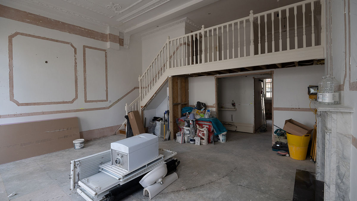 Before image of a London flat interior during refurbishment, with construction materials, exposed walls, and a visible staircase, indicating extensive renovation