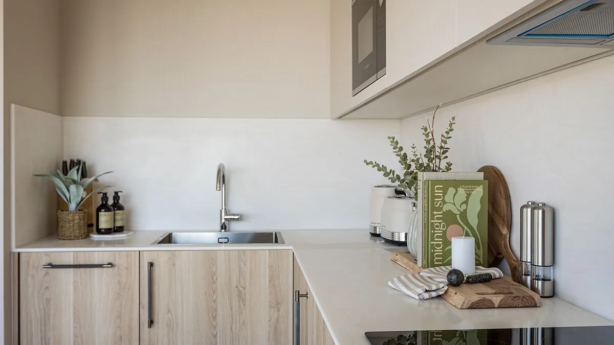 Modern minimalist kitchen with wood-finish cabinets, integrated appliances, quartz worktops, and stylish countertop accessories.